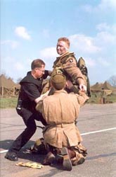 Major Robert L. Strayer (actor Phil McKee) being helped into his parachute harness.
