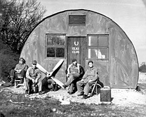 Nissen hut near the perimeter track. The propellers and tyre are from Piper L-4 Cubs. The man on the extreme right of the picture is Robert A. Stone who kindly supplied the photograph
